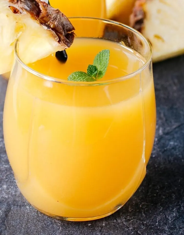 Pineapple mango juice being poured into a glass